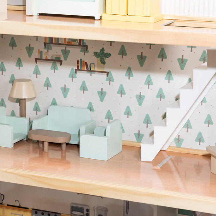 Interior de una casa de muñecas que muestra una sala de estar con muebles verde menta, una pared con papel tapiz de árboles verdes y una escalera blanca.