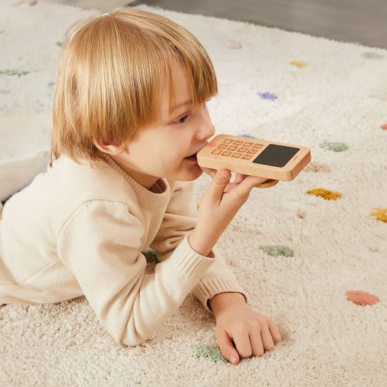 Niño pequeño jugando con celular de madera sustentable, juguete didáctico para fomentar el lenguaje y juego simbólico de imitación