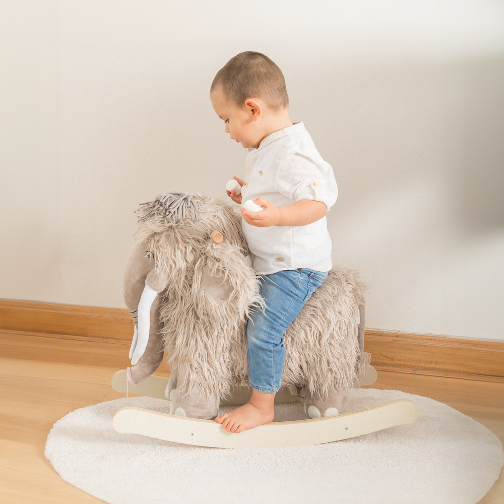 Niño meciéndose en el balancín mamut de madera de Roots Toys