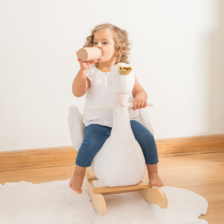 Niño meciéndose en el balancín cisne de madera de Roots Toys