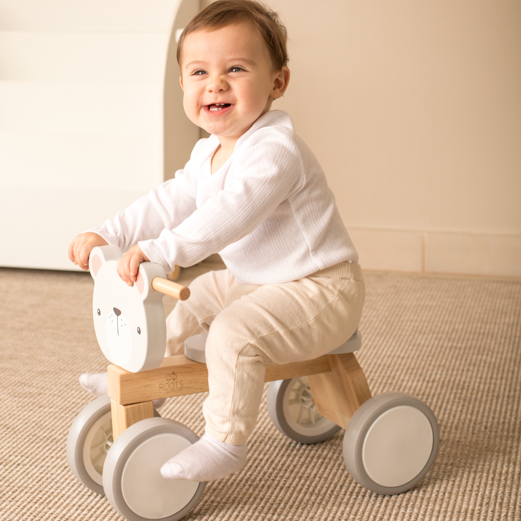Bebé jugando en correpasillos de madera Roots con forma de oso
