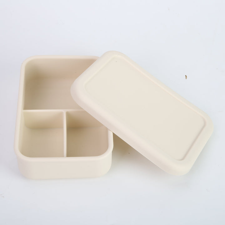 Lonchera de silicona crema abierta con tres divisiones internas. Caja bento moderna para organizar la colación de niños