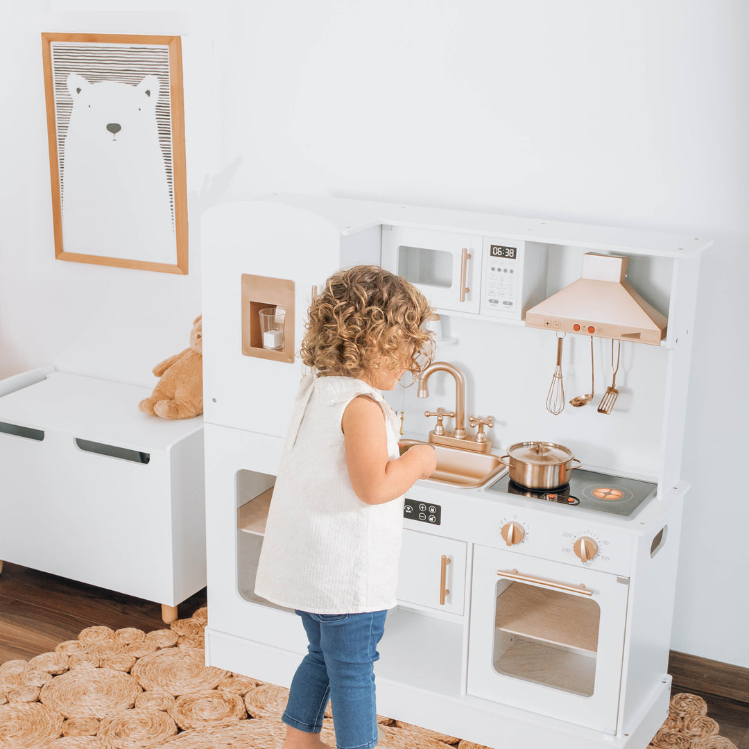 Niño jugando con la cocina de juguete Dominga de madera de Roots Toys