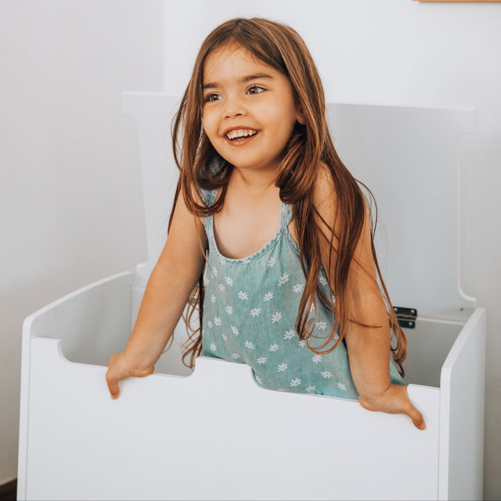 Primer plano de niña usando baúl juguetero de madera blanco, organizador de juguetes seguro y moderno