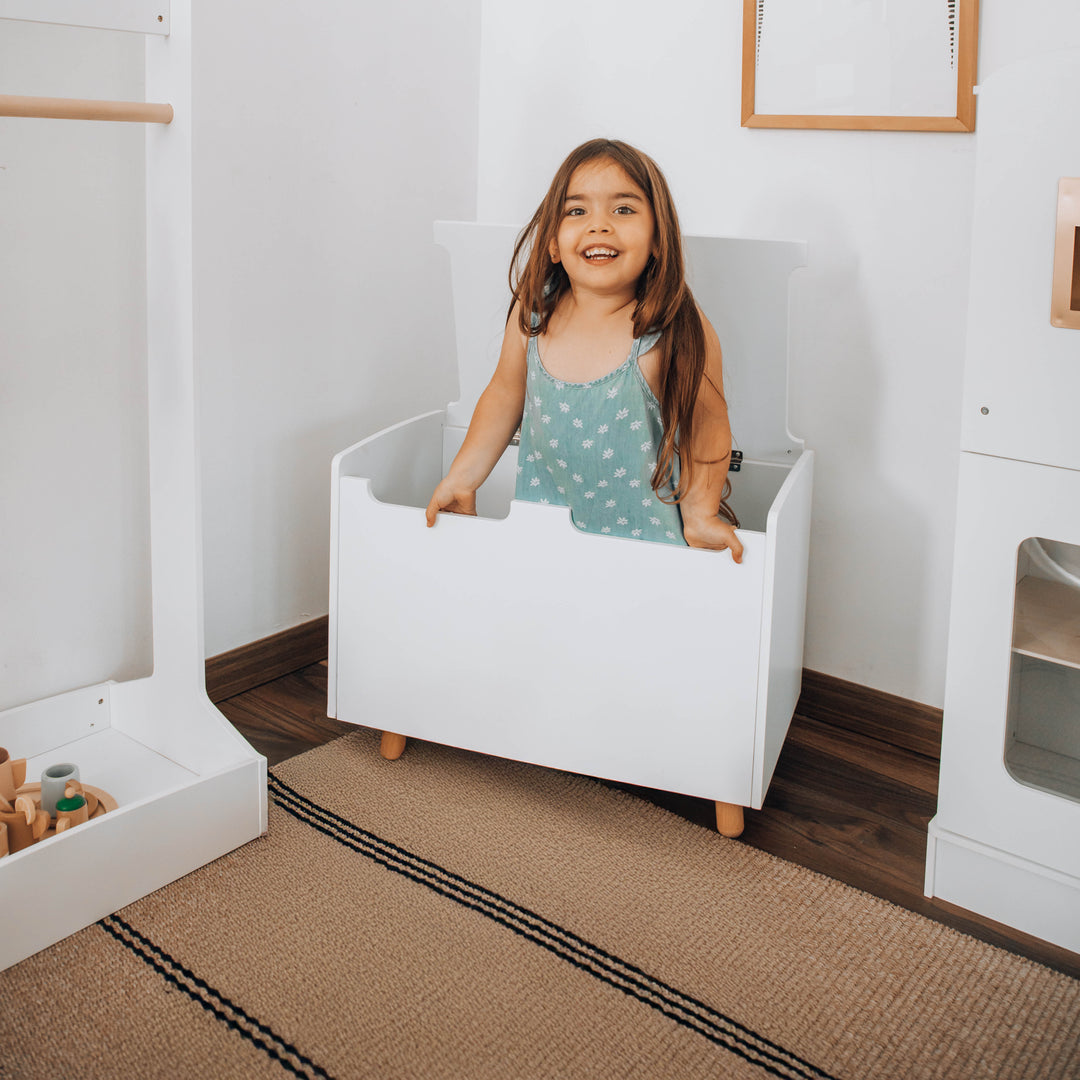 Niña jugando con baúl juguetero de madera blanco, organizador de juguetes con tapa de seguridad para dormitorios infantiles
