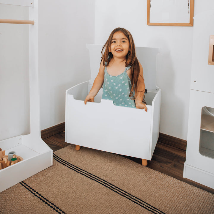 Niña jugando con baúl juguetero de madera blanco, organizador de juguetes con tapa de seguridad para dormitorios infantiles